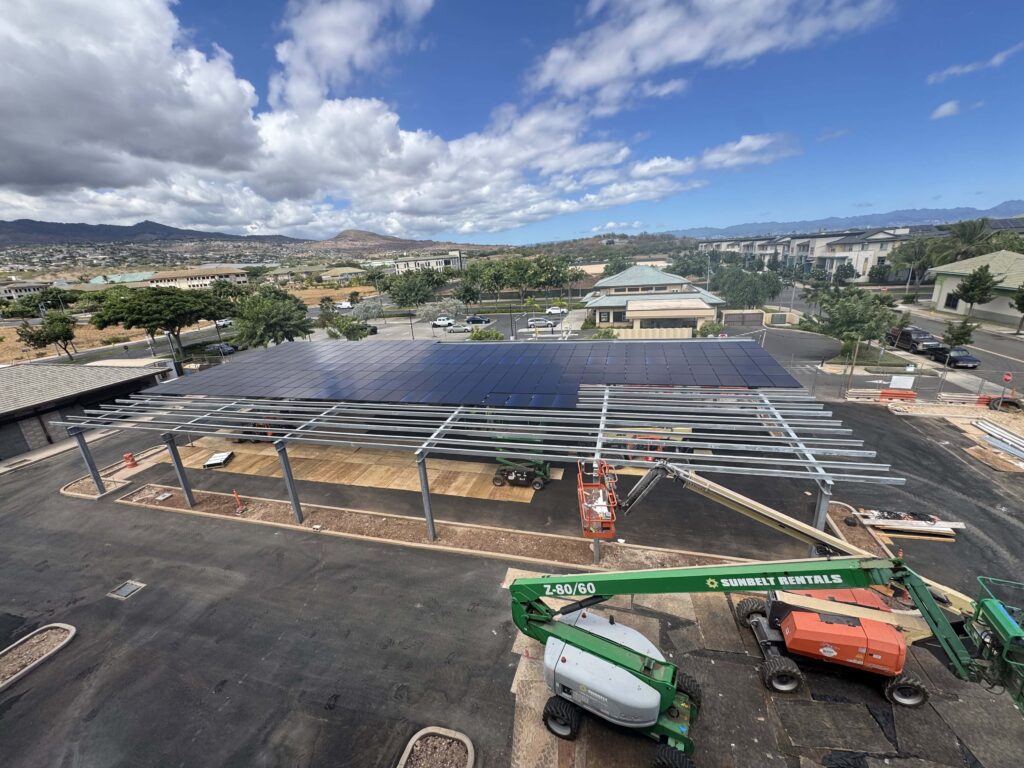 Solar carport under construction in a parking lot with a boom lift on Oʻahu